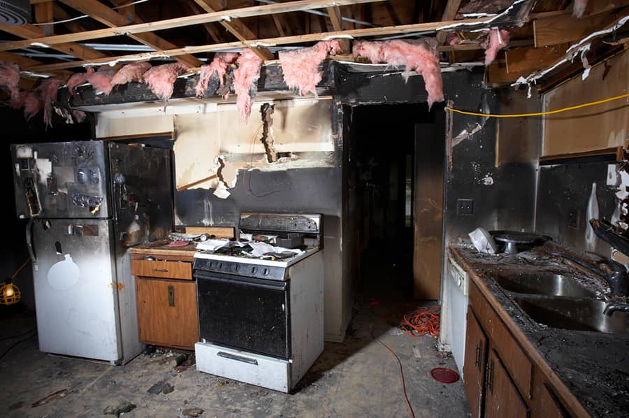 Fire damage cleanup crew removing debris and soot after a house fire