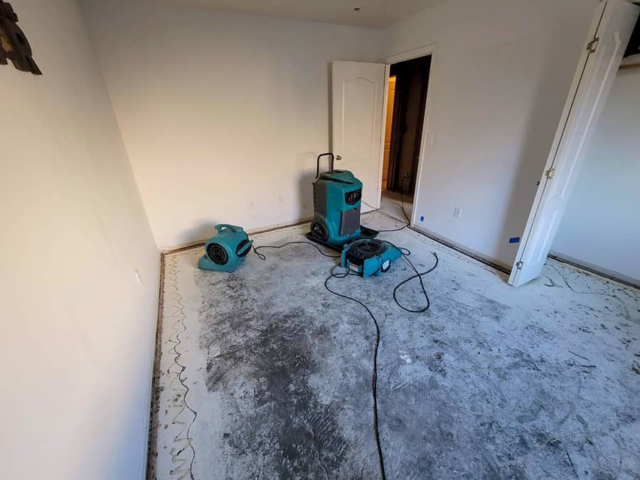 Water damage restoration Huntington Beach technician extracting water from a flooded room